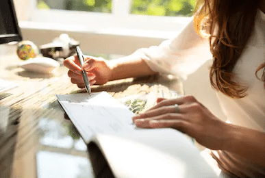 Family Lawyers - Woman writing in a check book on a sunny day